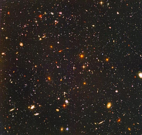 Una foto tomada por el telescopio espacial Hubble de miles de pequeñas galaxias de diferentes formas y colores.